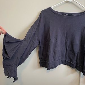 Cropped gray sweatshirt with ruffled sleeves.